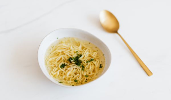 A Bowl of Noodles with a Spoon on a White Background
