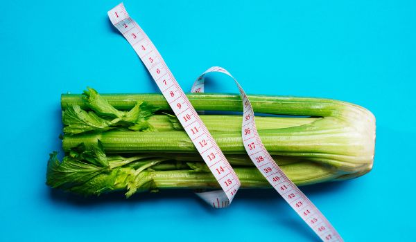 Fresh Celery Wrapped by an Inch-Tape on a Light Blue Background
