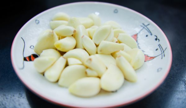 Peeled Cloves of Garlic in a Cute Plate on a Dark Table