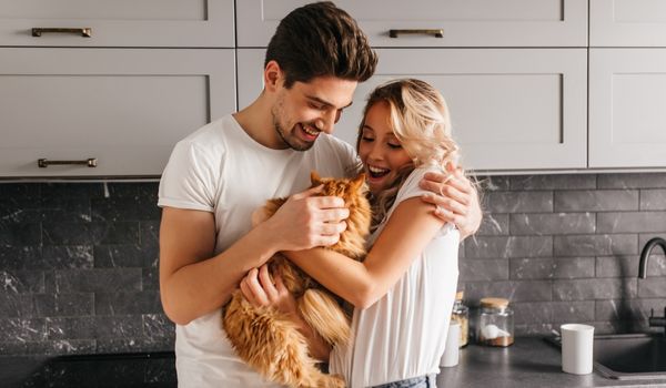 Portrait of a couple playing with their pet in the kitchen