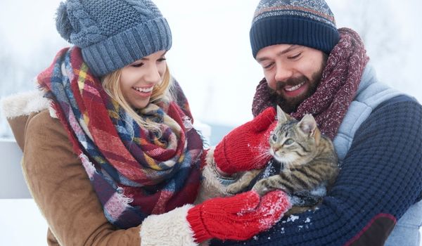 Smiling couple with a cat outside on winter day