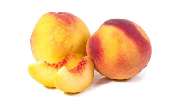Two whole peaches lie side-by-side next to two slices of peaches